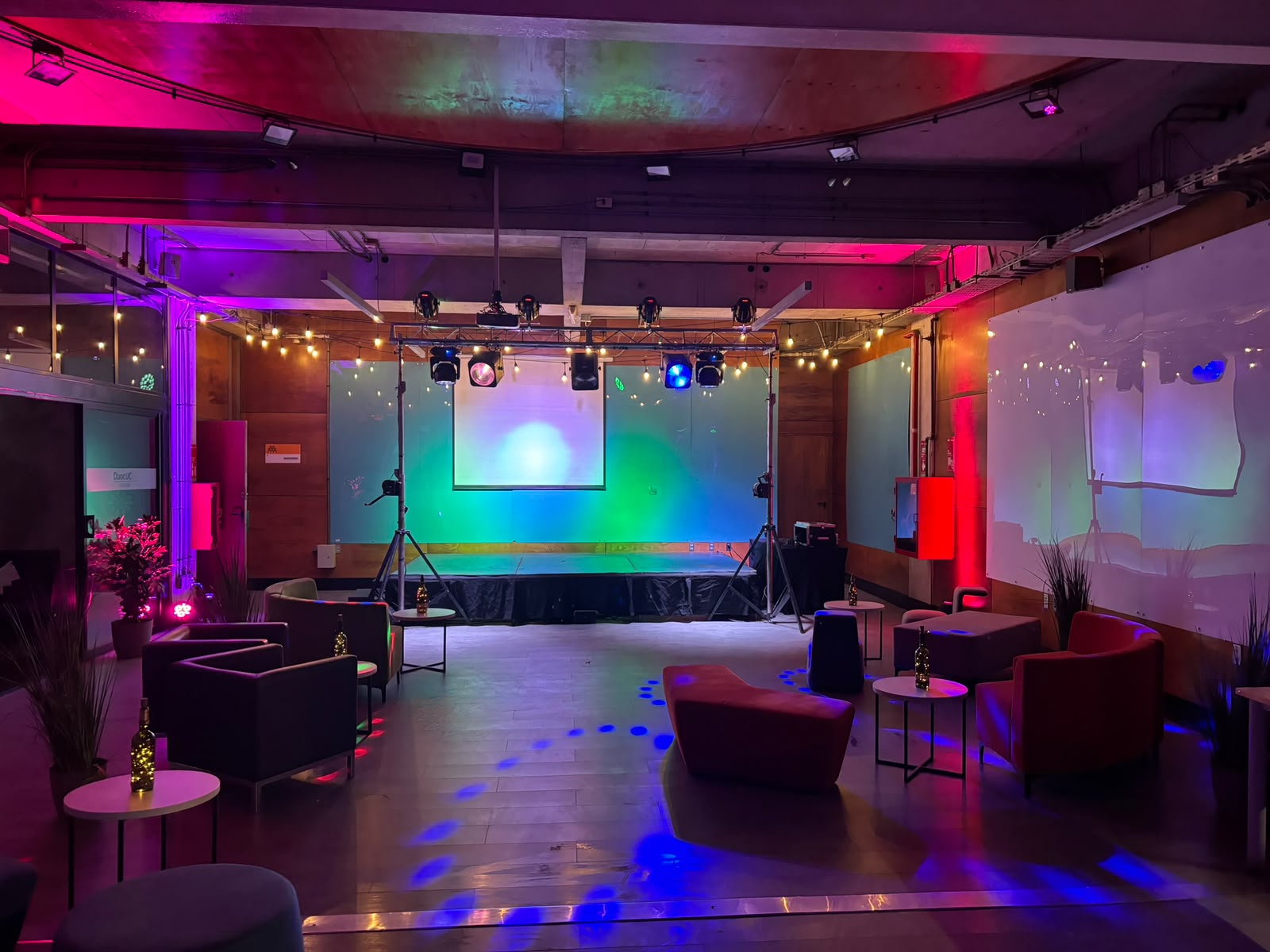 Escenario con iluminación robotizada y pantalla, montaje propio de Sincronízate Producciones