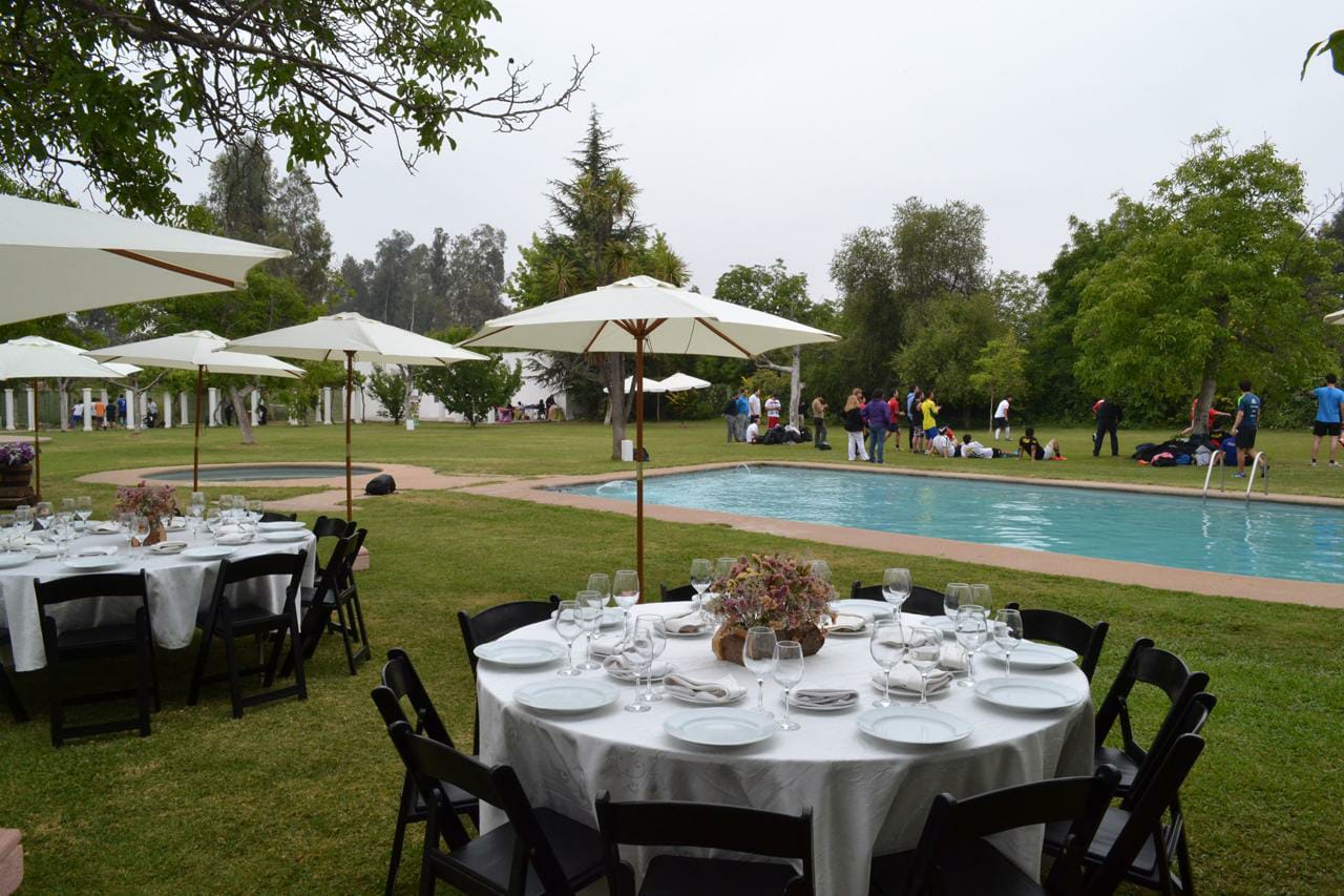 Mesas montadas junto a la piscina con servicio de coctelería para evento de día